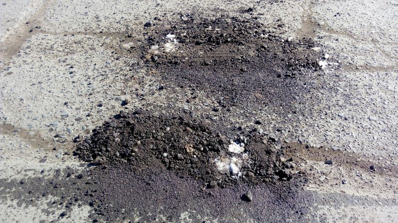 В Уральске ямы на дорогах засыпают старым асфальтом и льдом